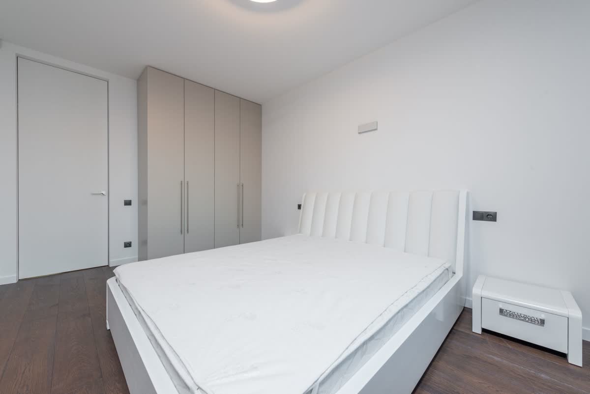 A bright, made bed in a minimal bedroom