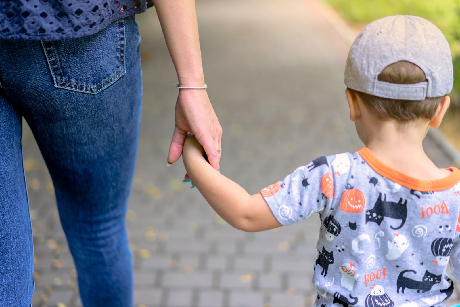 A parent holding a young child's hand while walking